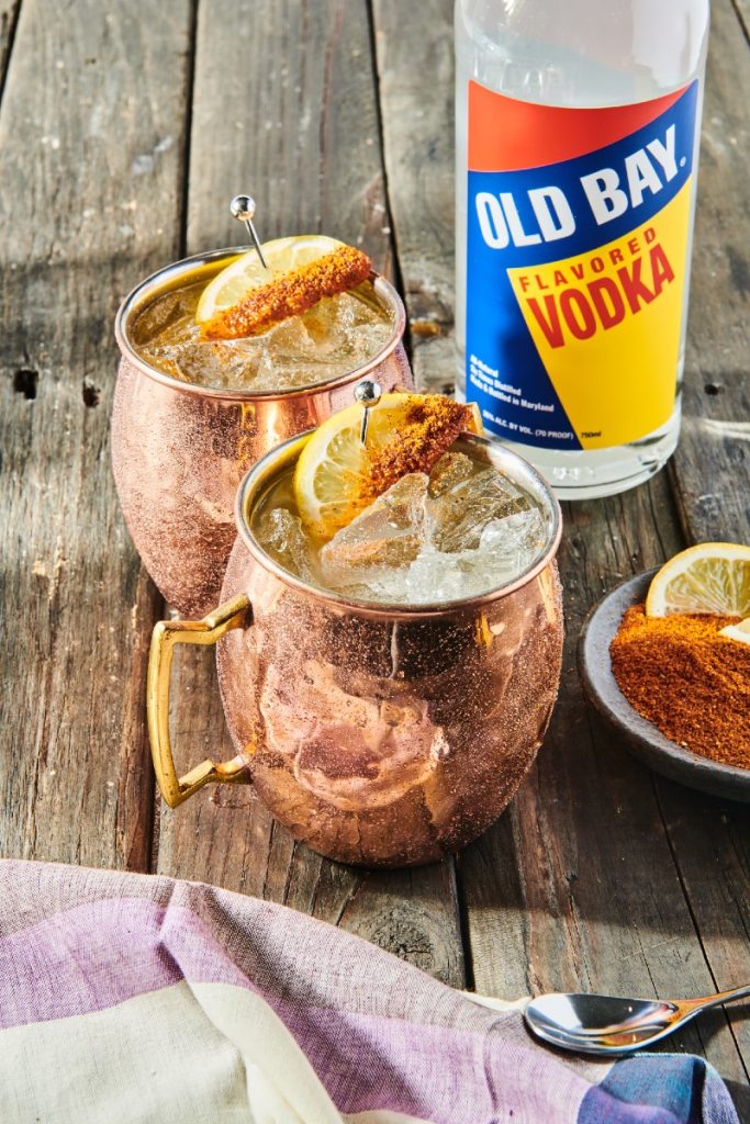 cocktail in copper mug with old bay vodka bottle and seasoning