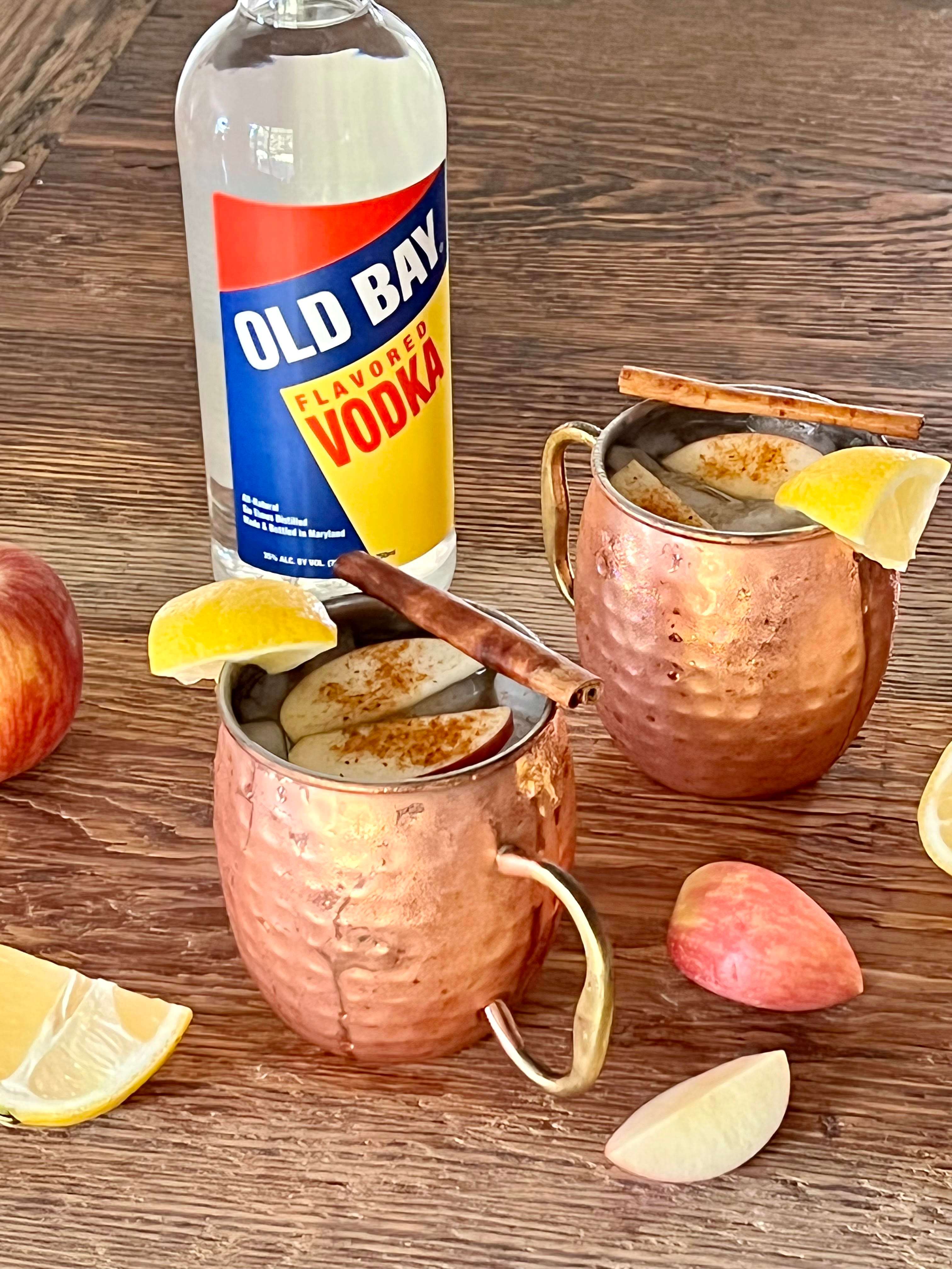 copper mugs with apples lemons and old bay vodka bottle