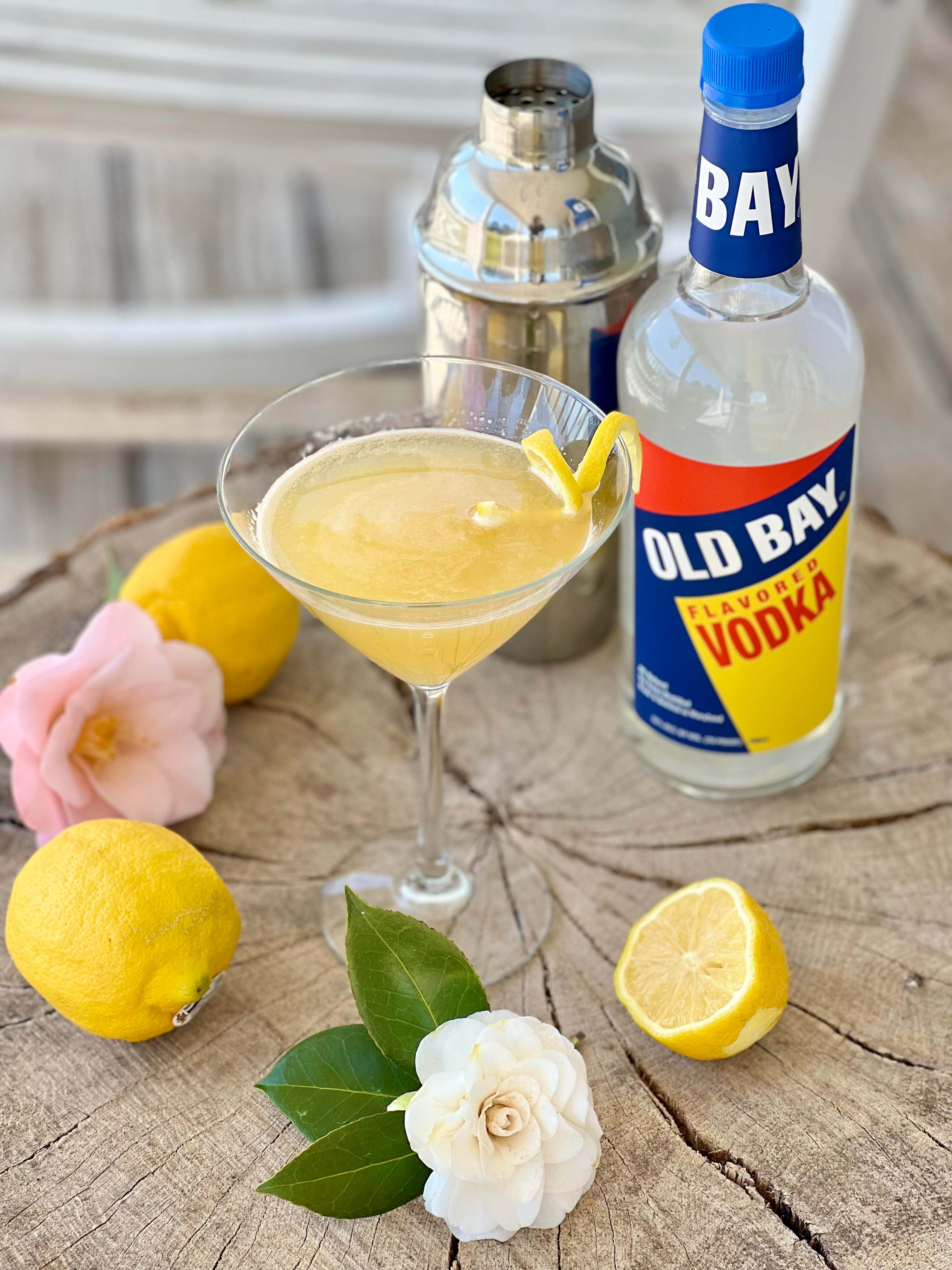 old bay vodka bottle with cocktail surrounded by lemons and flowers