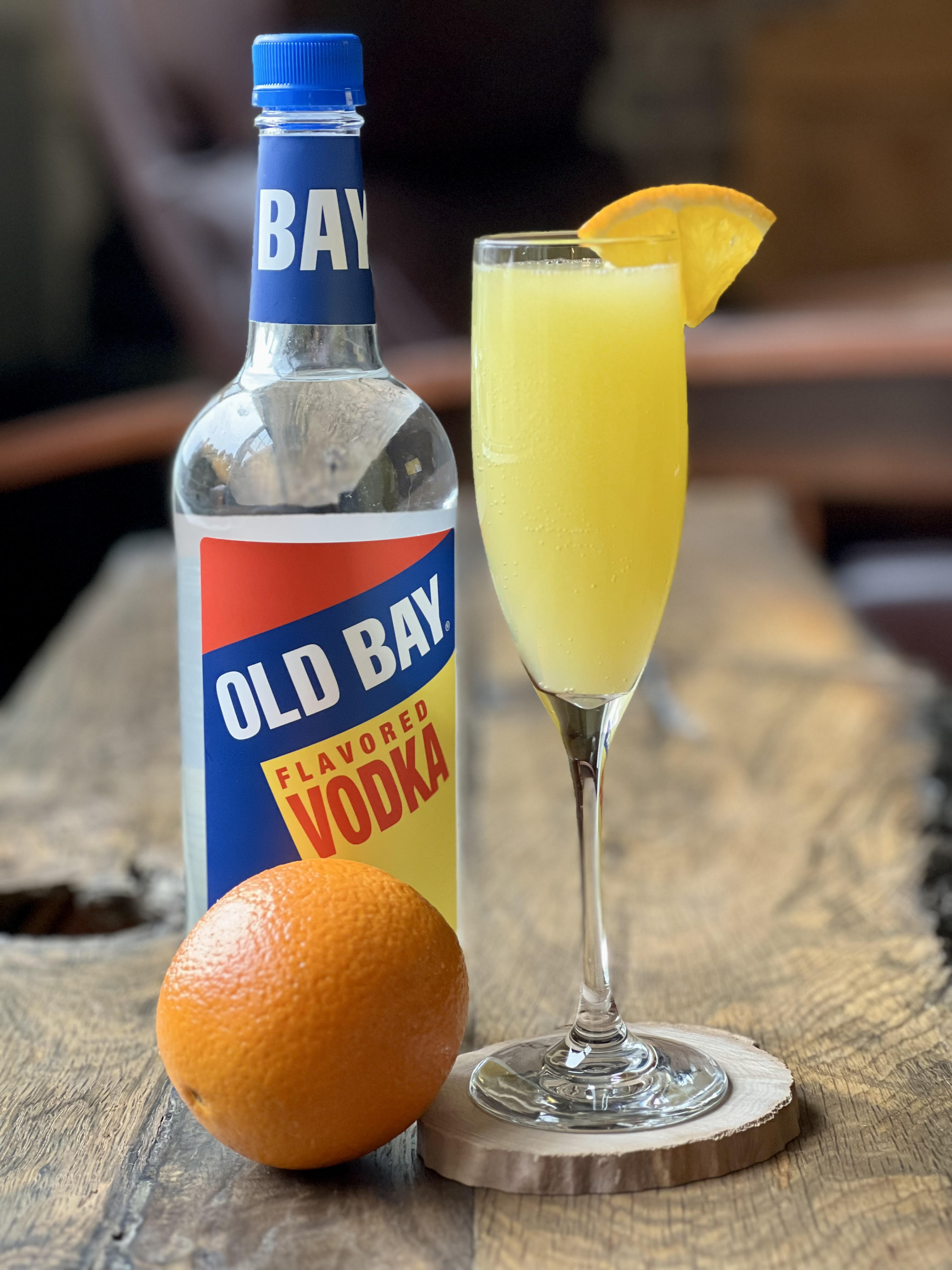 bellini cocktail with old bay vodka bottle and orange