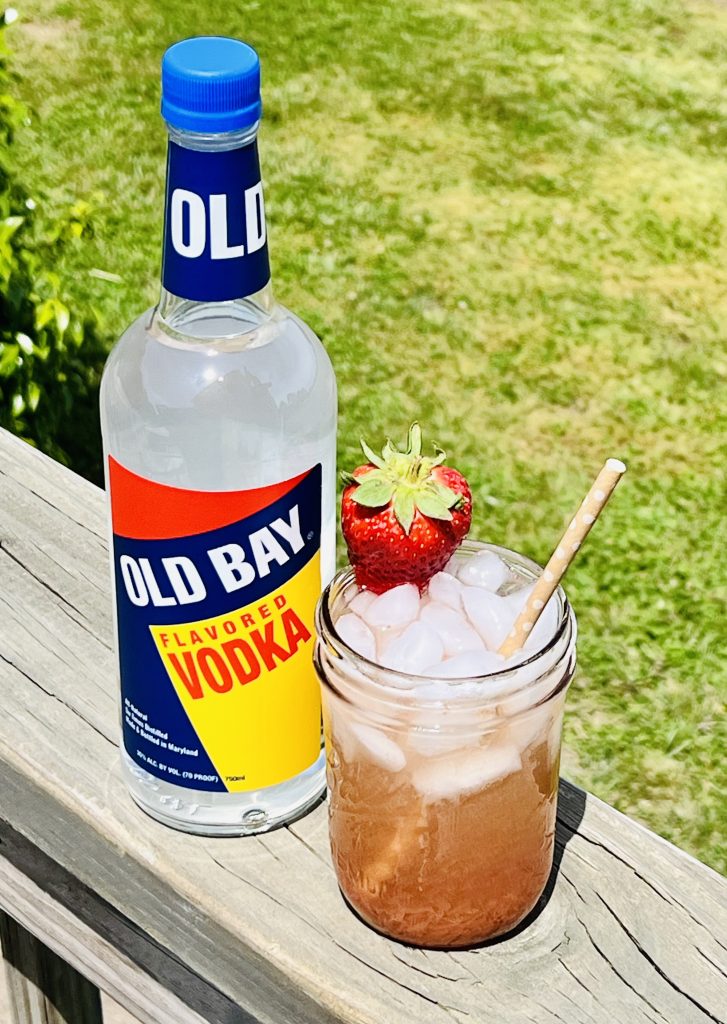 bottle of old bay vodka sitting next to mason jar filled with cocktail