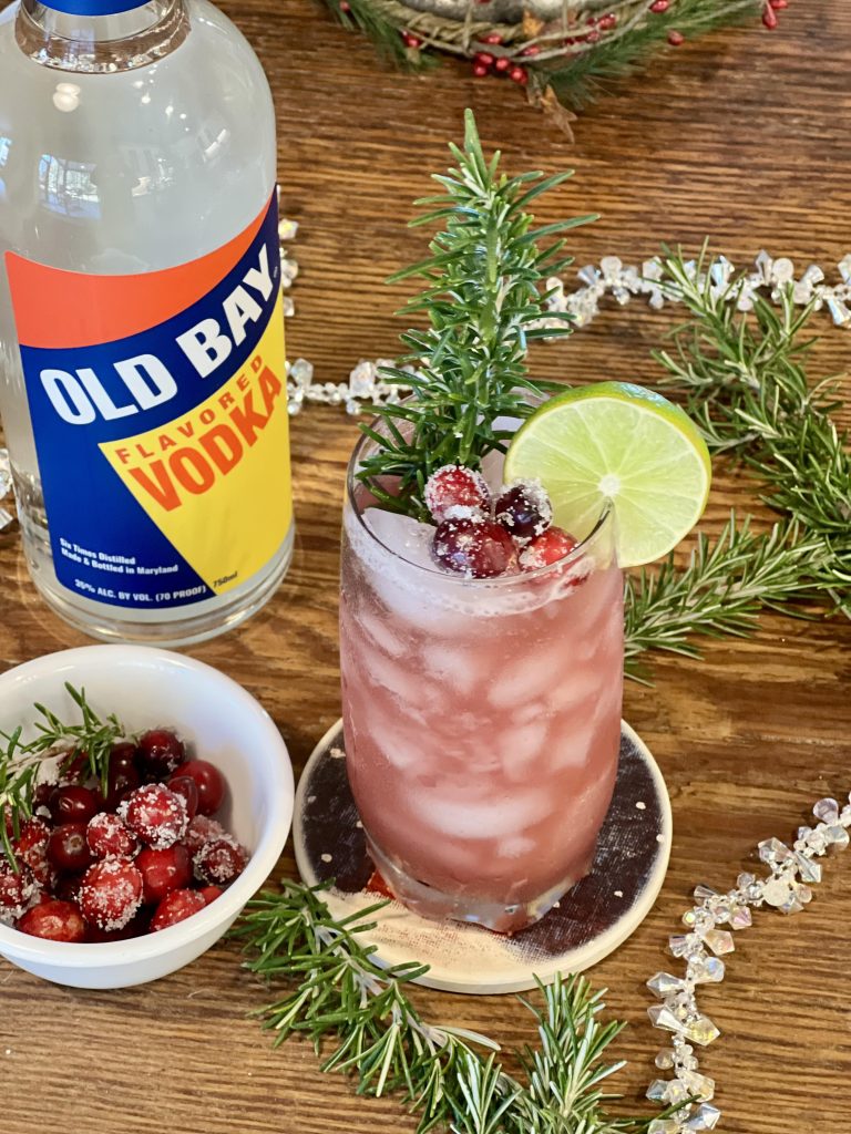 old bay vodka bottle with holiday cocktail and cranberries on table